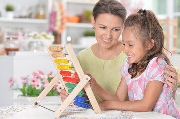 Mother teaching her daughter to use abacus indoors