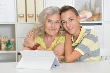 Grandson with grandmother with  tablet  at home