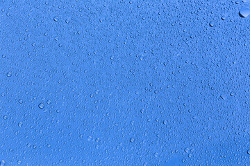 Water droplets condense on glass in the blue background.