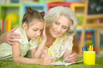 portrait of a cute little girl drawing with her grandmother