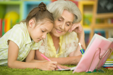 Little girl doing homework with her grandmother at home