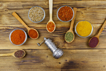 Set of different aromatic spices and spice mill on wooden table. Top view