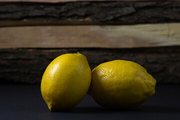 Lemon on a dark background. Two lemons on a wooden background. Creative photo of lemon.