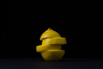 Fototapeta na wymiar Lemon on a dark background. Sliced lemon on a black background. Creative photo of lemon.