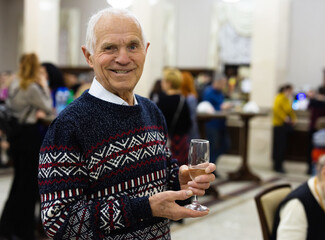 Elderly Senor drinking champagne and relaxing at lobby of theater at intermission