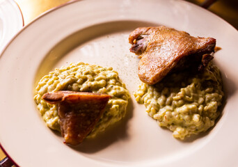 dish duck leg with green perlotto served on a white plate