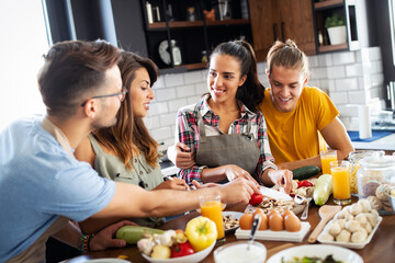 Young group of friends preparing vegetable meal and making fun.