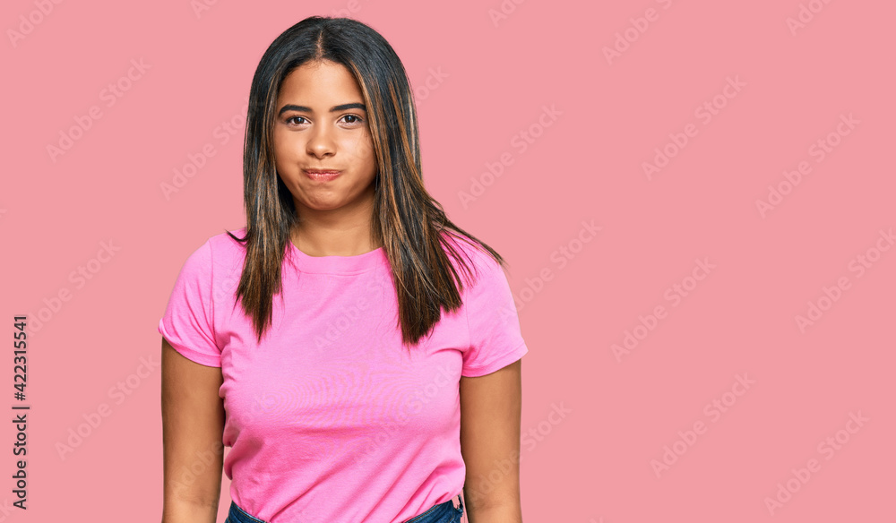 Wall mural Young latin girl wearing casual clothes puffing cheeks with funny face. mouth inflated with air, crazy expression.