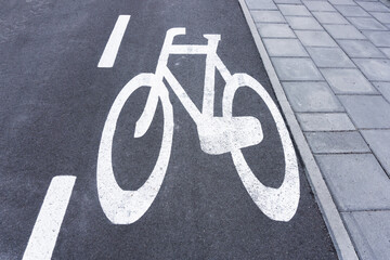 Obraz premium Bicycle lane background. Asphalt road for bikes. White paint bicycle painted on street. Pavement and bicycle lane. Walking and cycling path.