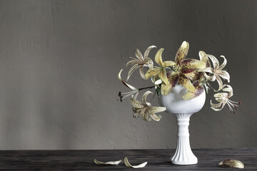 yellow lily in ceramic white vase on wooden table
