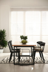 Stylish wooden dining table and chairs in room. Interior design