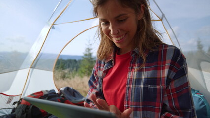 Girl shopping online on digital tablet in tent with mountains on background
