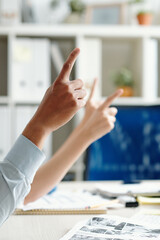 Business people sitting at meeting table and pointing with finger to ask speaker a question