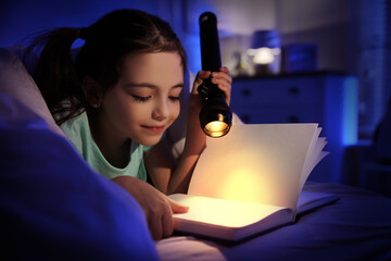 Little girl with flashlight reading fairy tale in dark bedroom - obrazy, fototapety, plakaty