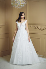 Bride in beautiful dress standing indoors interior at home. Trendy wedding style shot. Wedding makeup and hairstyle. Beautiful Bride in the morning.