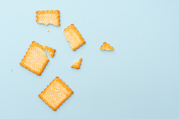 Broken dry cookies on blue background, top view, lay out