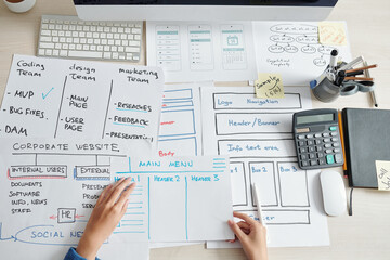 Project manager looking at drawings created by UI and UX designers and marketing department for new mobile application of company