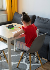 The girl draws in the kitchen from a video lesson. Home teaching, online lesson and Quarantine concept.