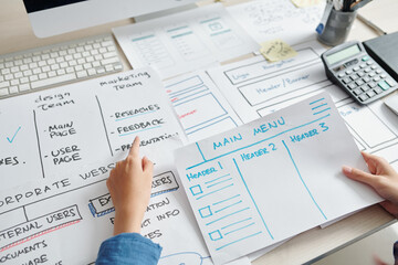 UX designer analyzing layouts in front of him when creating layout of website interface of new company