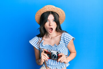 Young beautiful caucasian girl holding vintage camera afraid and shocked with surprise and amazed expression, fear and excited face.