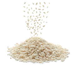 Sesame seeds falling into pile on white background