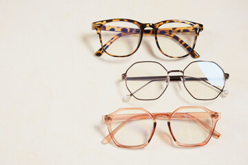 several fashionable stylish glasses on a beige background place copy top view, optics store
