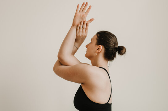 Upper body side portrait of woman doing eagle garudasana arms yoga pose on a white background. Concept: self care practices at home - Powered by Adobe