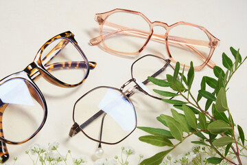 several fashionable glasses and flowers on a beige background copy space top view - obrazy, fototapety, plakaty