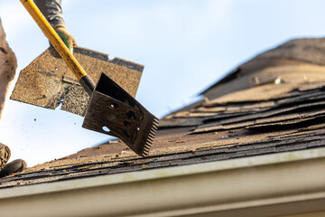 roofer removing roof nails with roof shingle remover