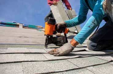 roofer installing roof shingles with nail gun