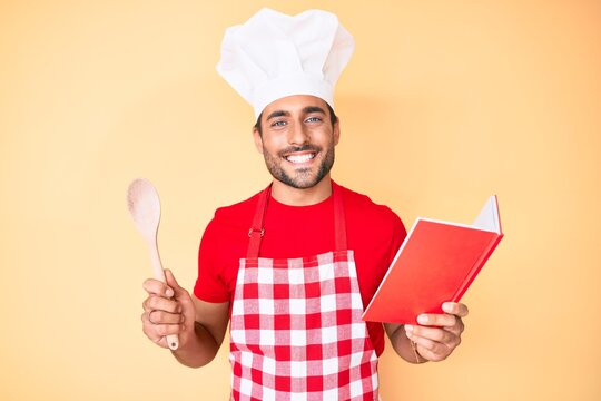 Young hispanic man wearing professional baker apron reading cooking recipe book smiling with a happy and cool smile on face. showing teeth.