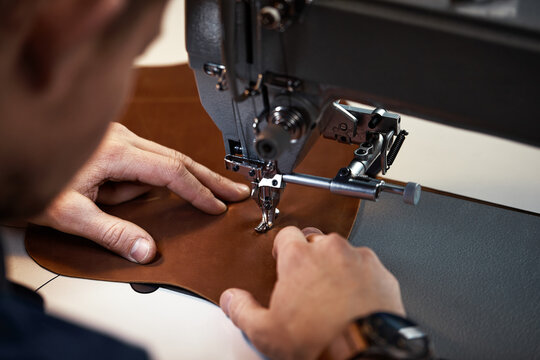 Working process of leather craftsman. Tanner or skinner sews leather on a special sewing machine, close up.worker sewing on the sewing machine
