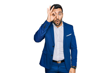 Young hispanic man wearing business jacket doing ok gesture shocked with surprised face, eye looking through fingers. unbelieving expression.