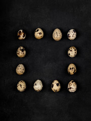 Geometric shapes from quail eggs on a black textured background. Square.