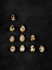 Geometric shapes from quail eggs on a black textured background. Triangle.