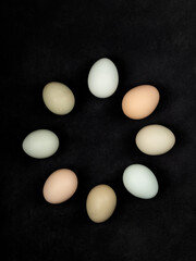 Fresh white chicken eggs in the shape of a circle, top view, on a black textured background. Creativity.
