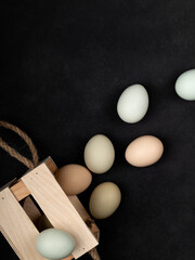 Fresh white chicken eggs in a wooden box, top view, on a black textured background. Healthy eating. Creativity.