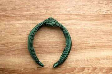 Green headband on wooden background. Flat lay.