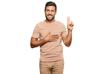 Handsome hispanic man wearing casual clothes smiling swearing with hand on chest and fingers up, making a loyalty promise oath