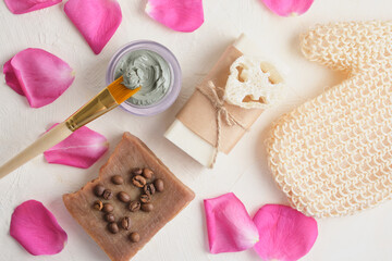 pink rose petals, cosmetic blue clay, washcloth, brush, loofah, cocoa soap and flowers on a light background spa concept