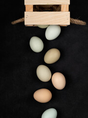 Fresh white chicken eggs in a wooden box, top view, on a black textured background. Healthy eating. Creativity.