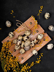 Layout with quail eggs on wooden board, on black textured background