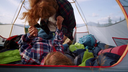 Positive couple lying in tourist tent. Happy man and woman cuddling each other