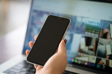 Women hand use smartphone with laptop background on table
