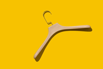 Plastic fashionable hanger under a tree on a yellow background with a hard shadow. Concept store, sale, design, empty hanger. Fashionable lightweight hangers made of durable material.