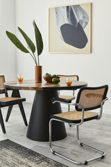 Stylish composition of dining room interior with design table, modern chairs, decoration, tropical leaf in vase, fruits, abstract mock up paintings and elegant accessories in home decor. Template.