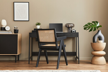 Modern interior design of home office space with stylish chair, desk, commode, black mock up poster...