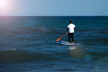 Man with surf board swimming in the sea. Water activity concept