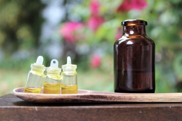 Cannabis oil, CBD oil, cannabis extract in 3 tiny containers and a glass with the oil on a wooden spoon. Blurred background in nature. Hemp oil. Medical and recreational use, marijuana concept outdoor