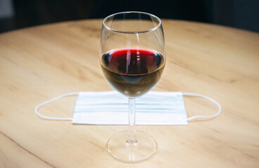 Medical mask near the a glass of wine. Alcoholic addict, Lost job, unemployment concept, economic crisis. Depression and alcoholism. Coronavirus (COVID-19)